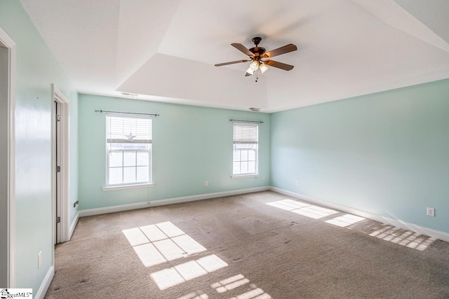 spare room featuring light colored carpet, a raised ceiling, a wealth of natural light, and ceiling fan