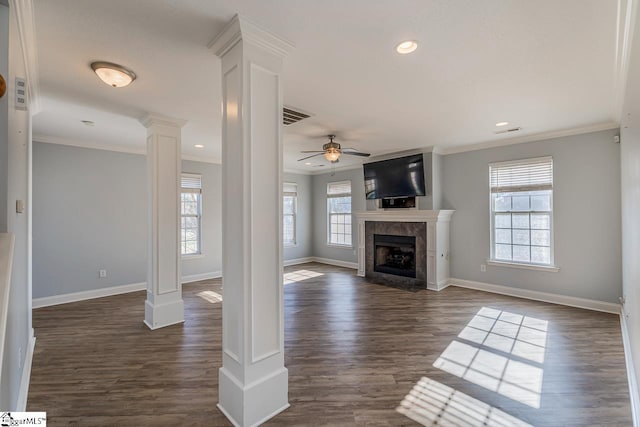 unfurnished living room with decorative columns, ceiling fan, crown molding, dark hardwood / wood-style floors, and a tiled fireplace