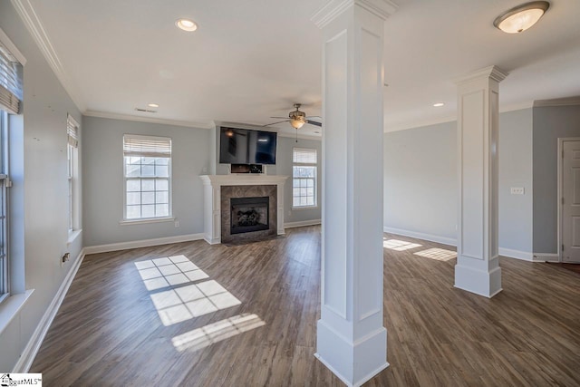 unfurnished living room with ceiling fan, dark hardwood / wood-style floors, decorative columns, a fireplace, and ornamental molding