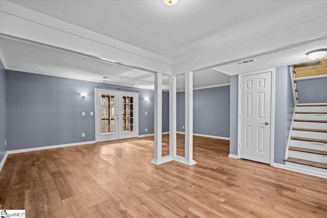 basement with french doors, a textured ceiling, and light hardwood / wood-style floors