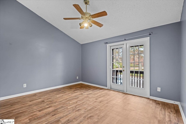 empty room with a textured ceiling, ceiling fan, light hardwood / wood-style floors, and vaulted ceiling