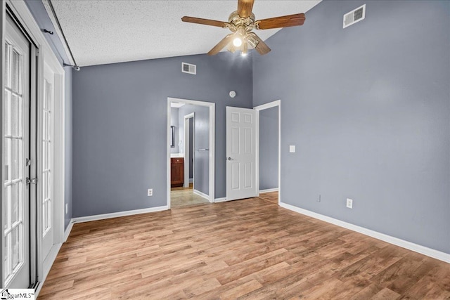 unfurnished bedroom featuring ceiling fan, french doors, high vaulted ceiling, light hardwood / wood-style floors, and a textured ceiling