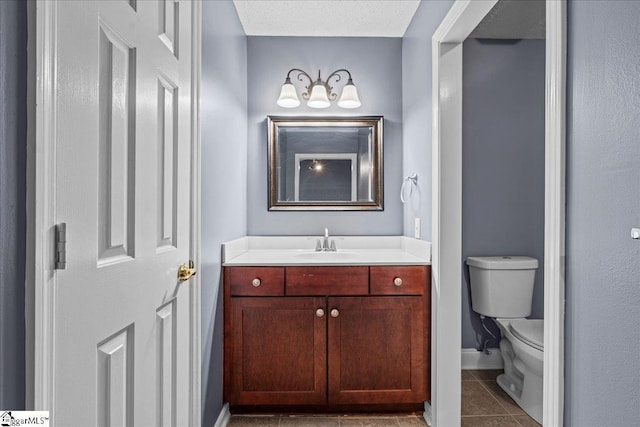 bathroom with tile patterned flooring, a textured ceiling, vanity, and toilet