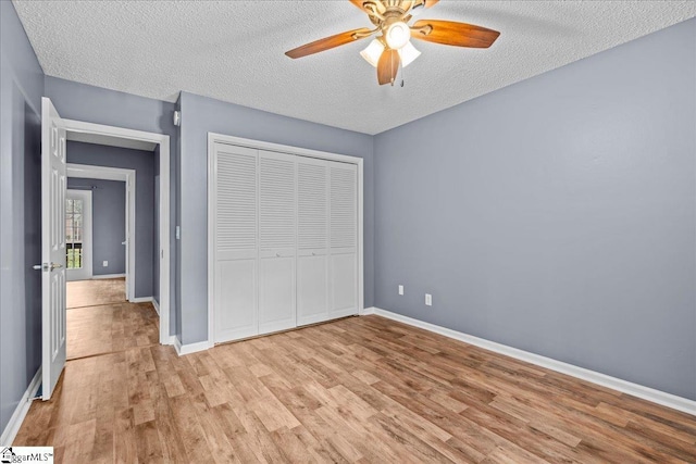 unfurnished bedroom featuring ceiling fan, a closet, light hardwood / wood-style floors, and a textured ceiling