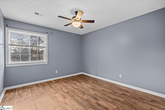 empty room with ceiling fan, wood-type flooring, and a textured ceiling