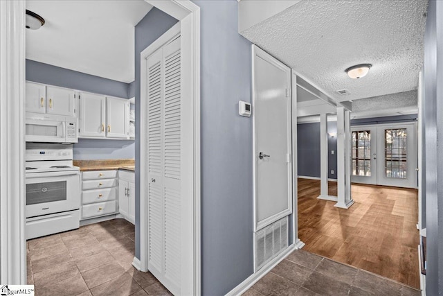 kitchen featuring white cabinets, french doors, white appliances, and a textured ceiling