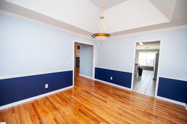 unfurnished room featuring wood-type flooring, crown molding, and a tray ceiling