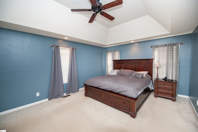 bedroom featuring lofted ceiling, a tray ceiling, ceiling fan, and light colored carpet