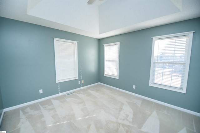 carpeted spare room featuring a tray ceiling