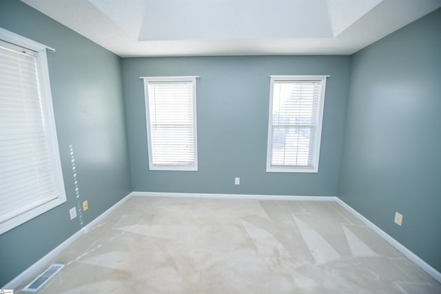 carpeted empty room featuring a raised ceiling