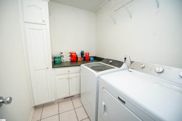 clothes washing area featuring cabinets, independent washer and dryer, and light tile patterned floors