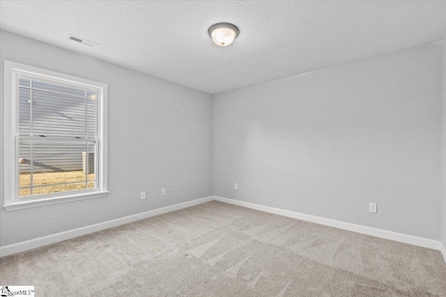 carpeted empty room with a textured ceiling