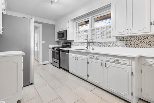 kitchen with tasteful backsplash, sink, white cabinets, and appliances with stainless steel finishes