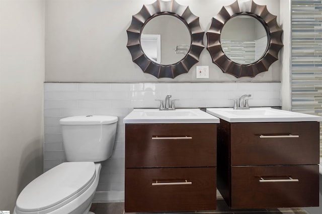 bathroom with vanity, toilet, and tile walls