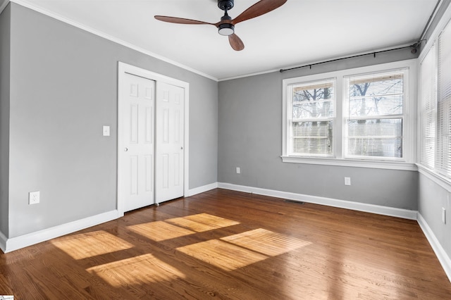 unfurnished bedroom featuring hardwood / wood-style floors, a closet, ceiling fan, and crown molding