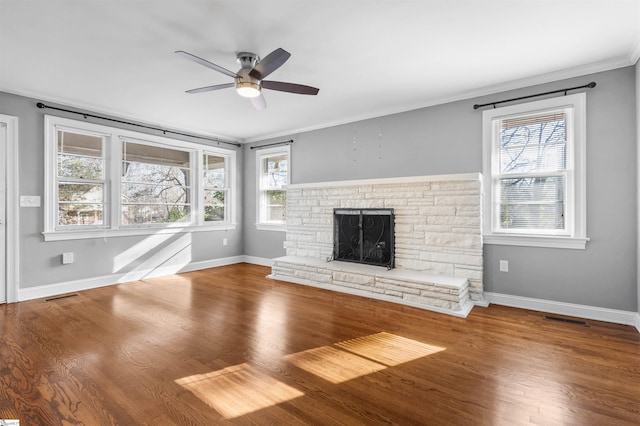 unfurnished living room featuring a fireplace, wood-type flooring, ceiling fan, and crown molding