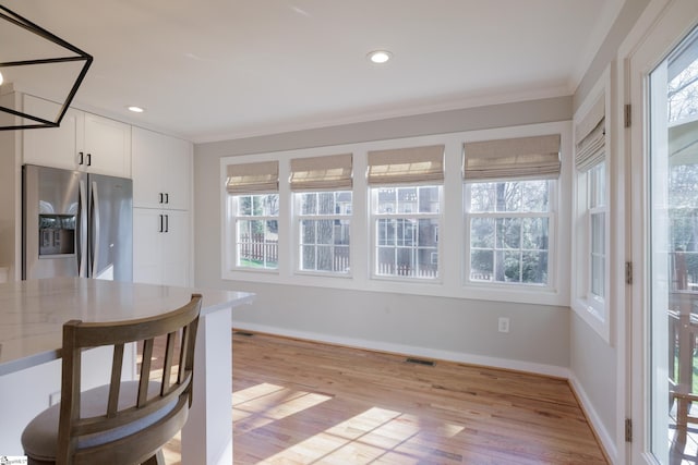 kitchen featuring stainless steel fridge, light hardwood / wood-style flooring, white cabinets, and light stone counters