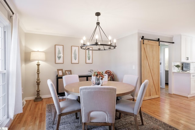 dining area featuring a barn door, ornamental molding, and light hardwood / wood-style flooring