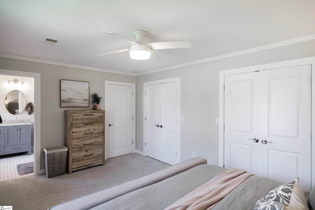 carpeted bedroom with multiple closets, connected bathroom, ceiling fan, and crown molding