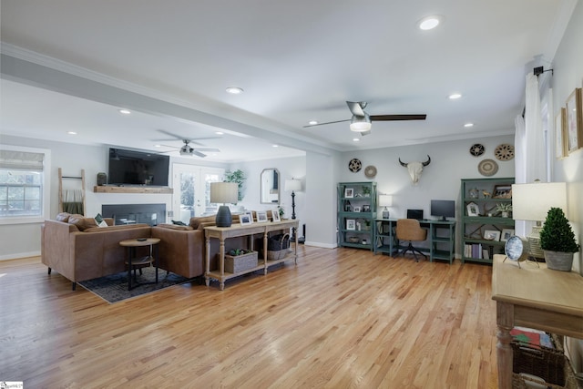 living room featuring ceiling fan, light wood-type flooring, and crown molding