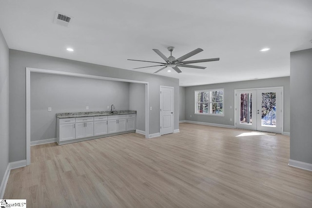 unfurnished living room featuring french doors, light wood-type flooring, and ceiling fan