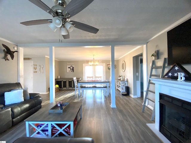 living room with a fireplace, ceiling fan with notable chandelier, hardwood / wood-style flooring, and ornamental molding