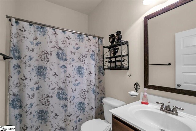 bathroom with walk in shower, vanity, and toilet