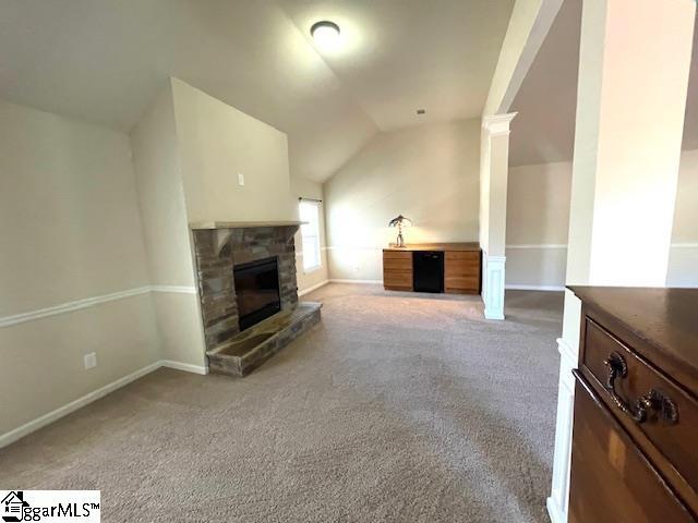 unfurnished living room featuring a stone fireplace, light carpet, and vaulted ceiling