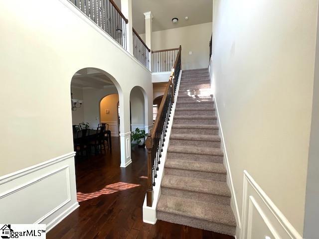 stairway with hardwood / wood-style floors and a towering ceiling