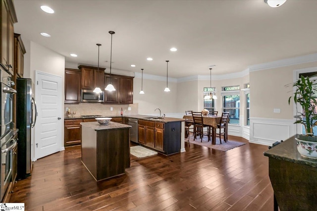 kitchen featuring a center island, sink, stainless steel appliances, pendant lighting, and ornamental molding