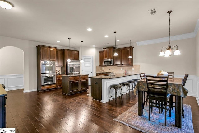 kitchen with kitchen peninsula, stainless steel appliances, decorative light fixtures, a chandelier, and a breakfast bar area