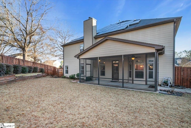 rear view of property with a patio area, a sunroom, and solar panels