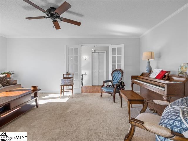 living area featuring ceiling fan, french doors, light colored carpet, and ornamental molding