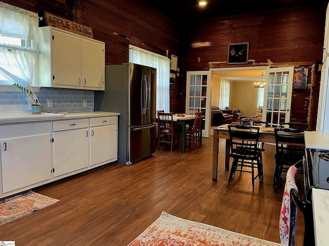 kitchen with white cabinetry, hanging light fixtures, dark hardwood / wood-style floors, backsplash, and stainless steel fridge