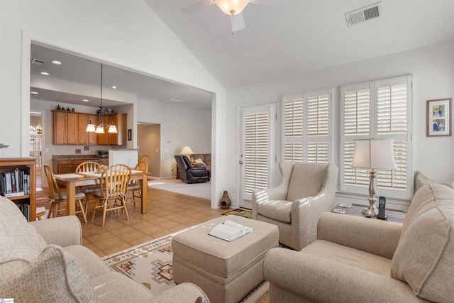 living room with ceiling fan with notable chandelier, light tile patterned floors, and high vaulted ceiling