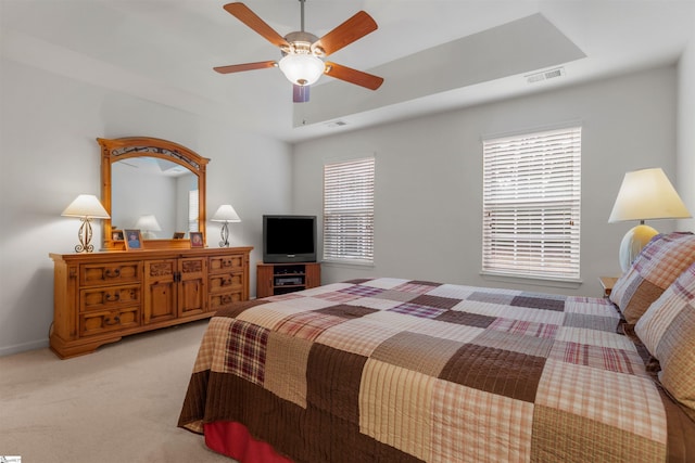 bedroom featuring a tray ceiling, ceiling fan, and light colored carpet