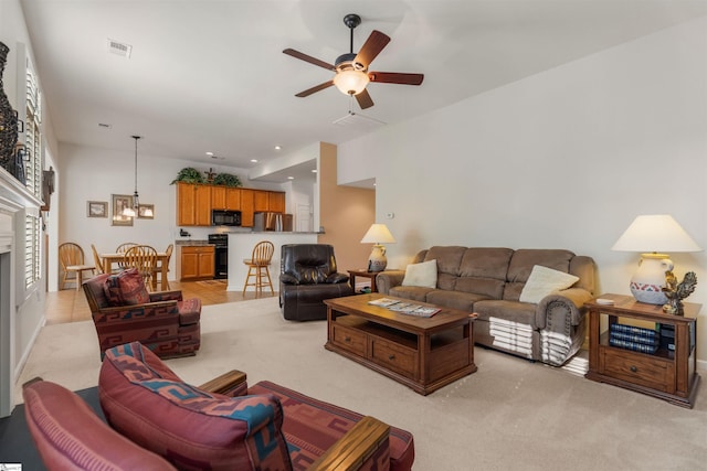 living room with ceiling fan with notable chandelier, light colored carpet, and plenty of natural light