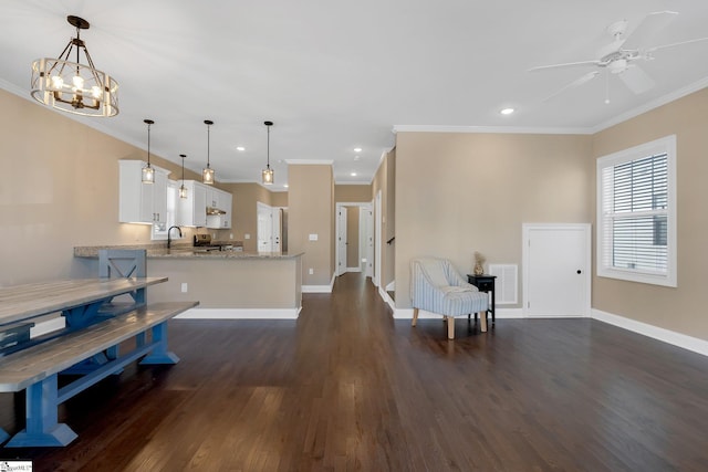 kitchen featuring kitchen peninsula, light stone countertops, white cabinets, and pendant lighting