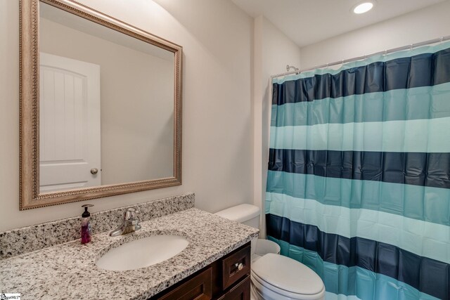 bathroom featuring toilet, vanity, and walk in shower