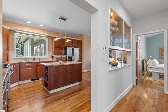 kitchen featuring sink, hanging light fixtures, appliances with stainless steel finishes, tasteful backsplash, and a kitchen island