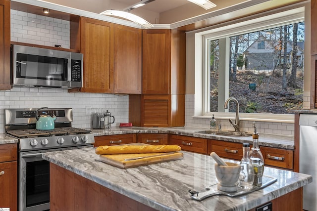 kitchen featuring decorative backsplash, light stone countertops, sink, and appliances with stainless steel finishes