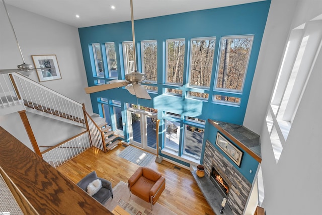 living room featuring ceiling fan, french doors, a fireplace, and light hardwood / wood-style flooring