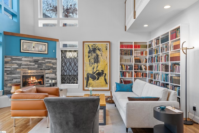 living area with a fireplace, hardwood / wood-style floors, and a towering ceiling