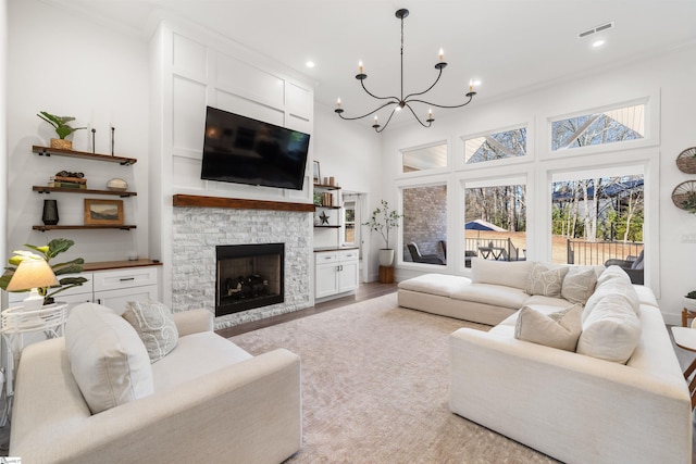 living room with a chandelier, ornamental molding, a fireplace, and light hardwood / wood-style flooring