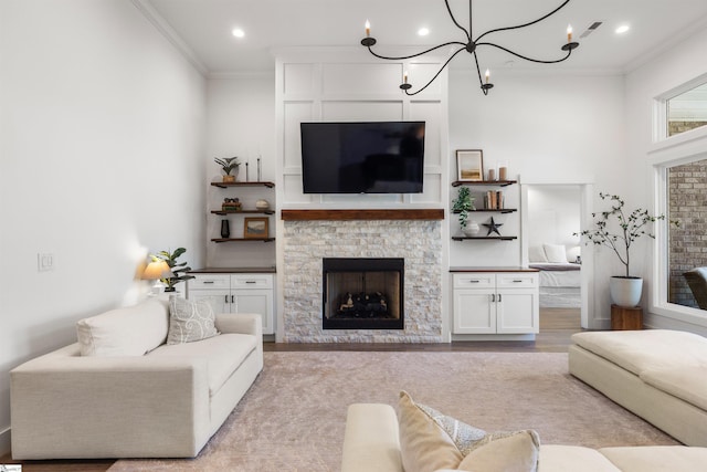 living room with a stone fireplace, light wood-type flooring, crown molding, and a chandelier