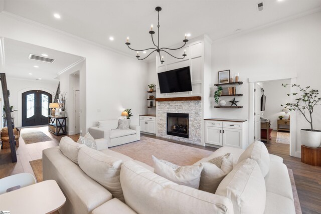 living room with an inviting chandelier, light wood-type flooring, a fireplace, and french doors