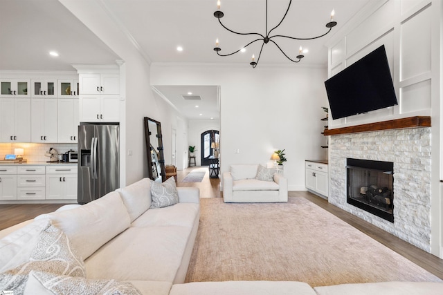 living room featuring a fireplace, light hardwood / wood-style floors, a notable chandelier, and ornamental molding