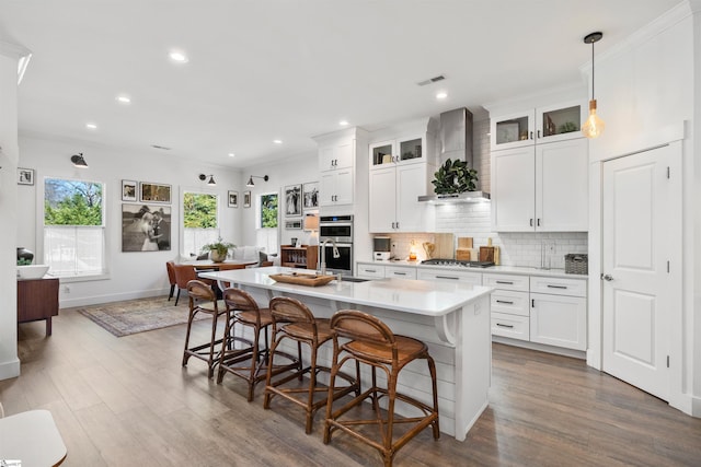 kitchen with white cabinets, appliances with stainless steel finishes, and wall chimney range hood