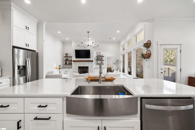 kitchen featuring a fireplace, appliances with stainless steel finishes, an inviting chandelier, and white cabinetry