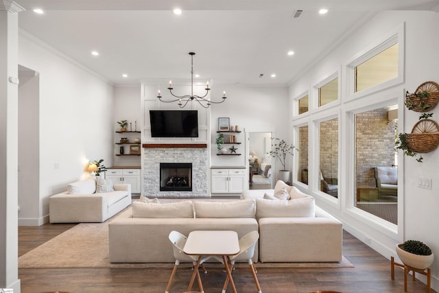 living room with a fireplace, dark hardwood / wood-style floors, an inviting chandelier, and ornamental molding